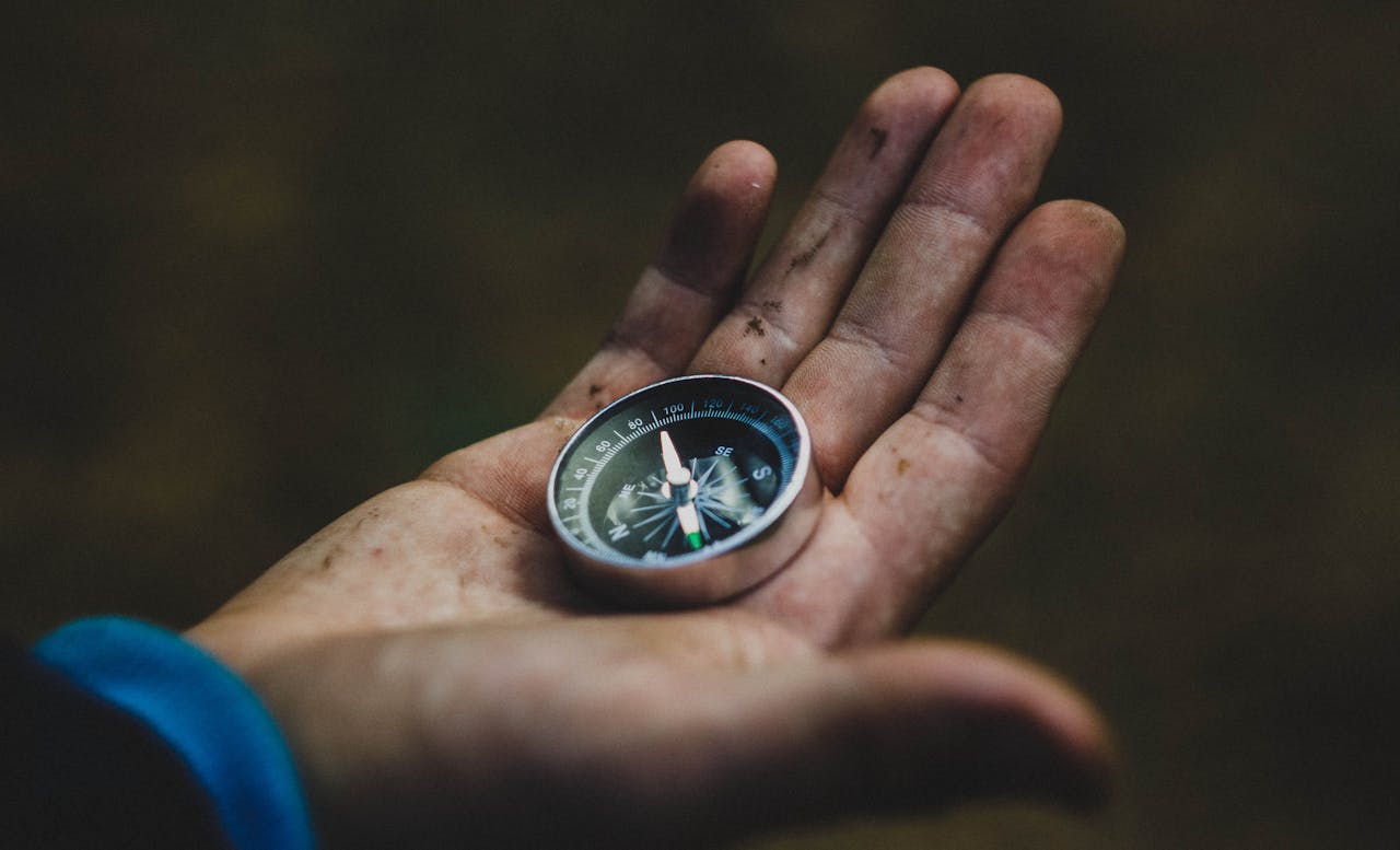 why-choose-us A close-up of a compass held in a dirty hand, symbolizing adventure and navigation.
